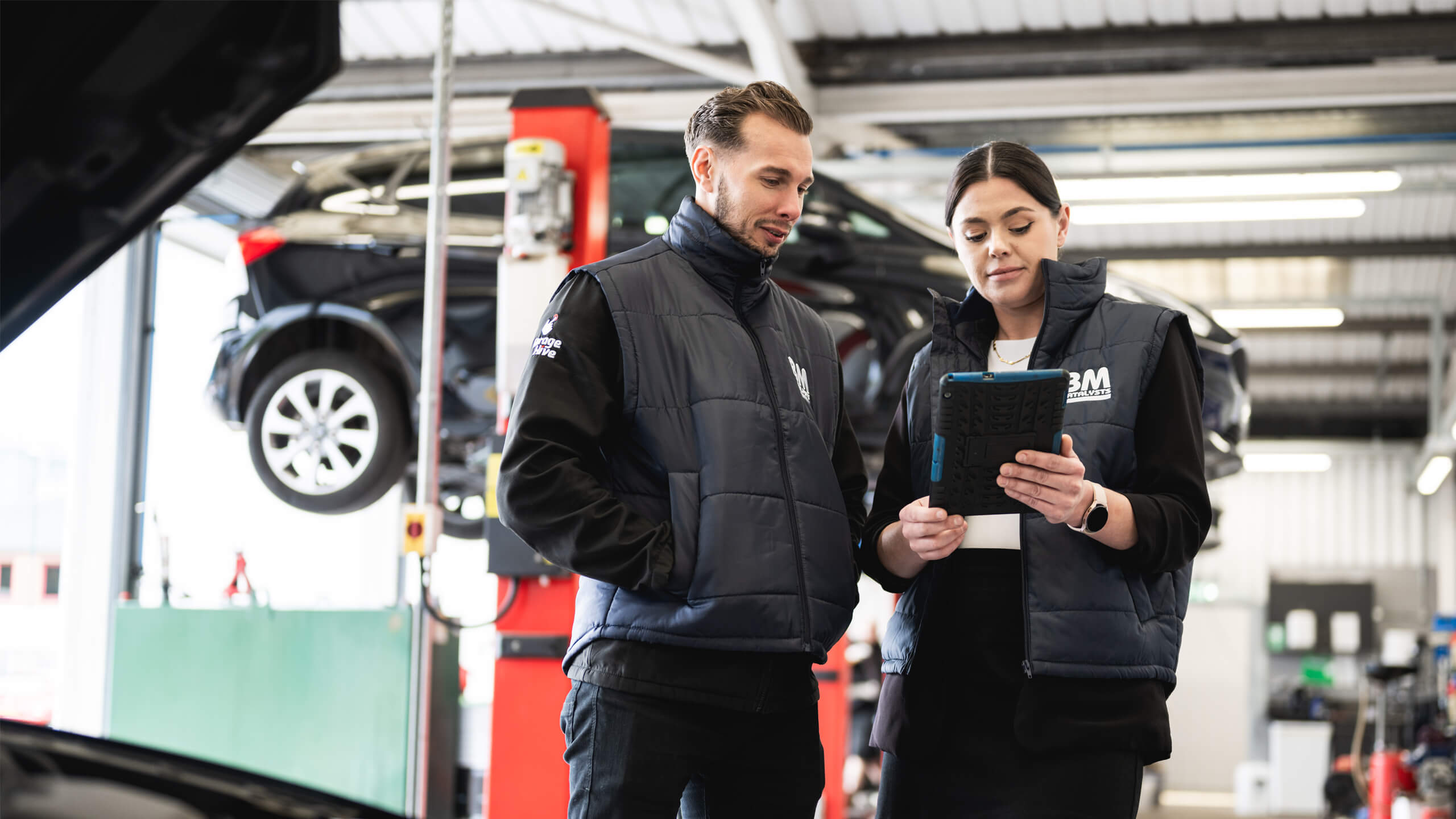 Garage employees with BM clothing using tablet